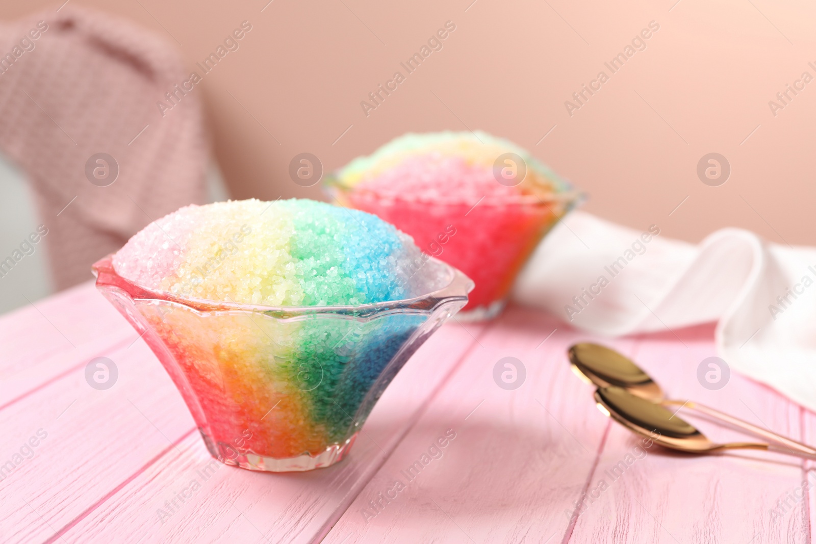 Photo of Rainbow shaving ice in glass dessert bowls on pink wooden table indoors