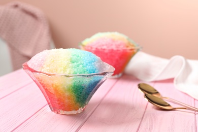 Photo of Rainbow shaving ice in glass dessert bowls on pink wooden table indoors