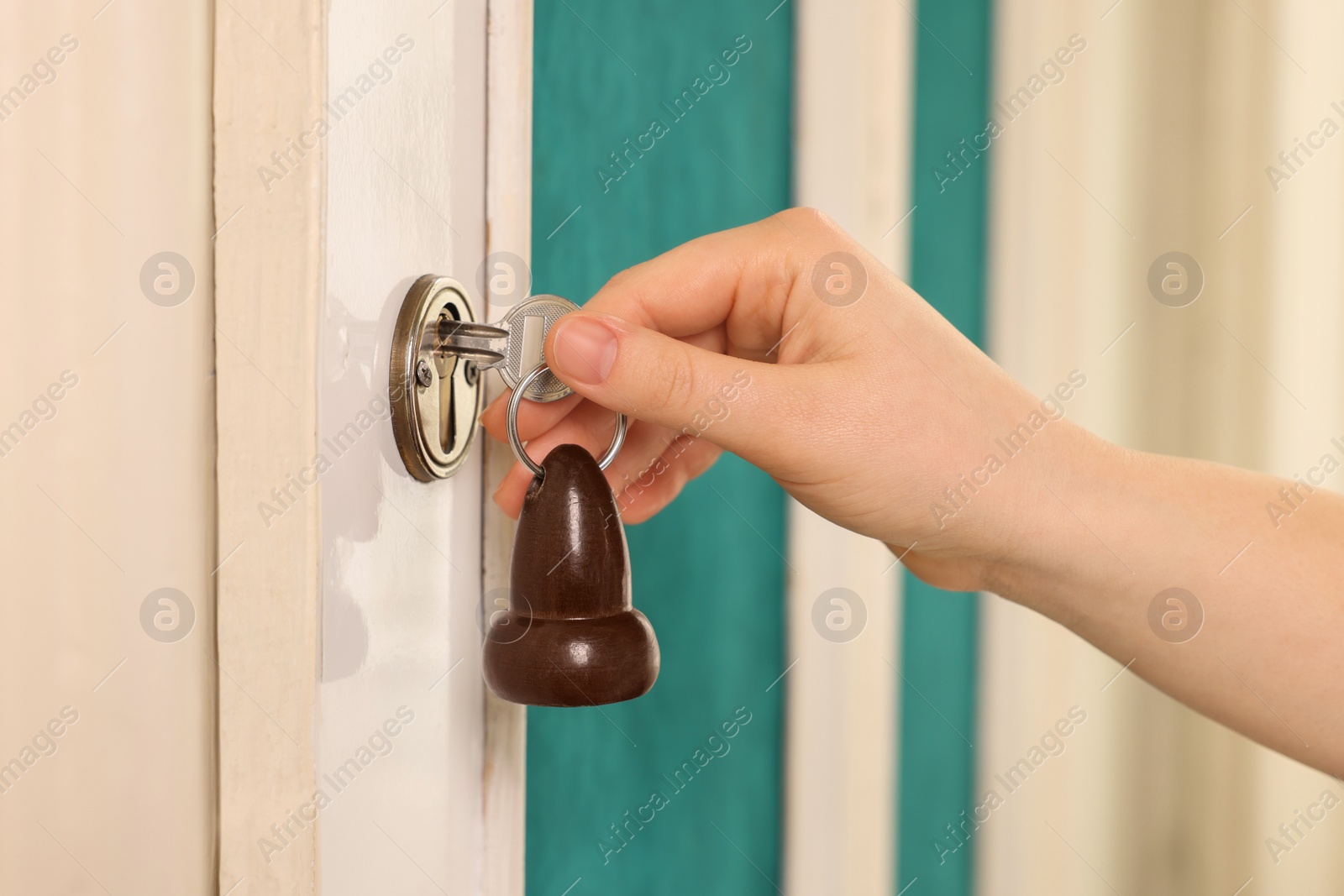 Photo of Woman opening door with key outdoors, closeup