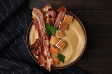 Photo of Delicious lentil soup with bacon and parsley in bowl on wooden table, top view