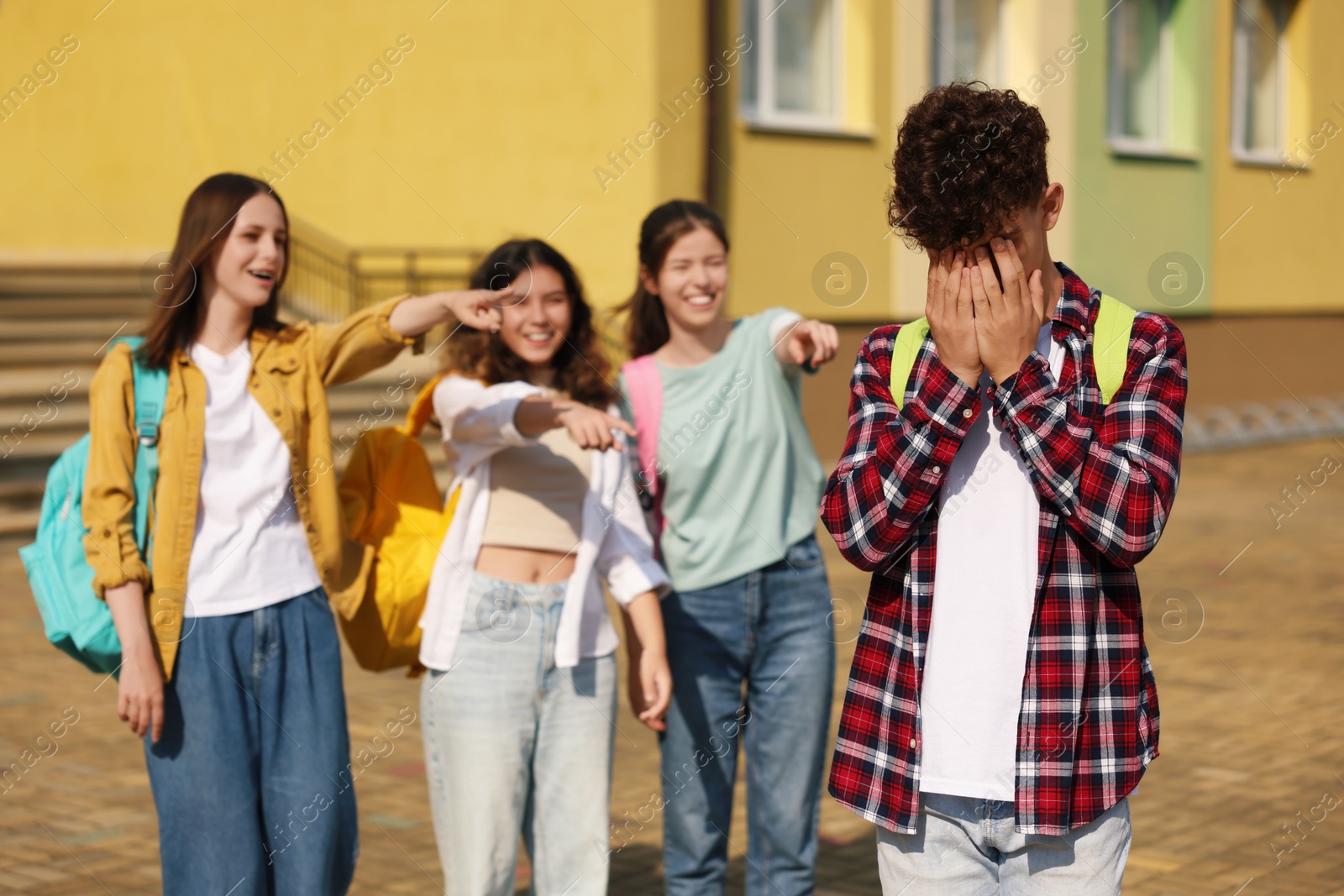 Photo of Teen problems. Group of students pointing at upset boy outdoors, selective focus