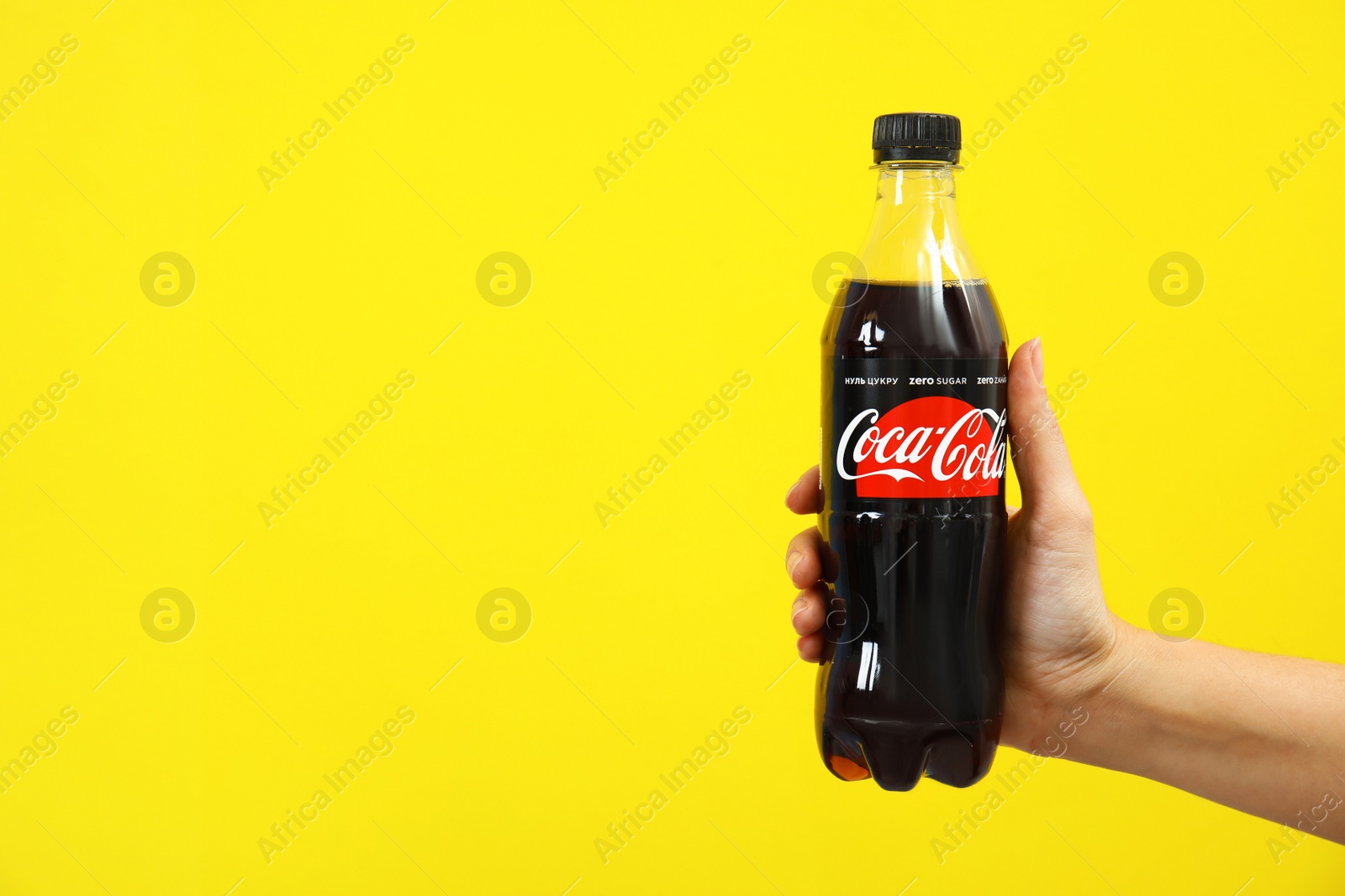 Photo of MYKOLAIV, UKRAINE - NOVEMBER 14, 2018: Woman holding bottle of Coca-Cola on color background. Space for text