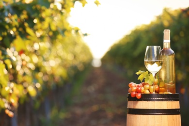 Photo of Composition with wine and ripe grapes on barrel outdoors. Space for text