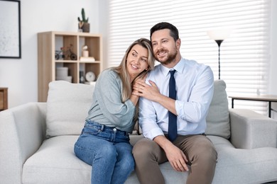 Happy couple sitting on sofa at home