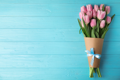 Photo of Beautiful pink spring tulips on light blue wooden background, top view. Space for text