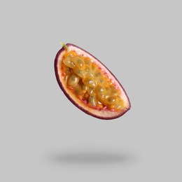 Piece of passion fruit falling on light grey background