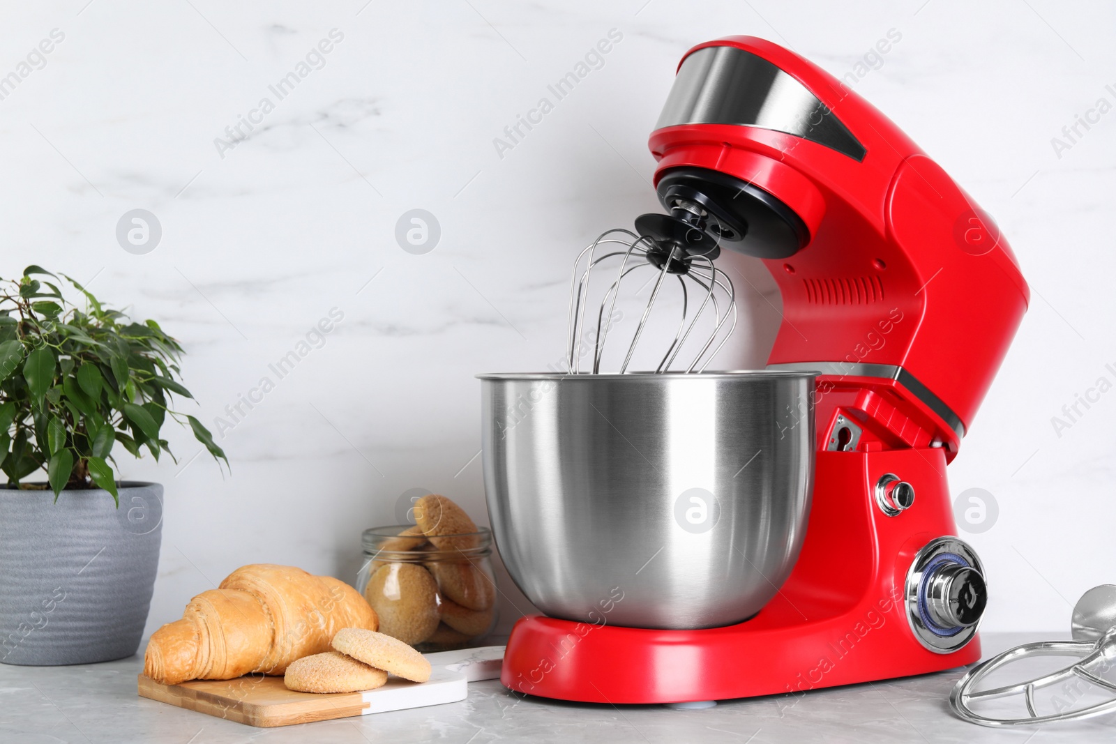 Photo of Modern red stand mixer, croissant and cookies on light gray marble table