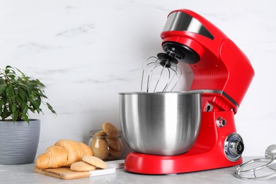 Photo of Modern red stand mixer, croissant and cookies on light gray marble table