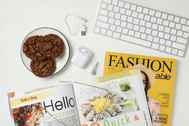 Photo of Workplace with modern magazines on white wooden table, flat lay