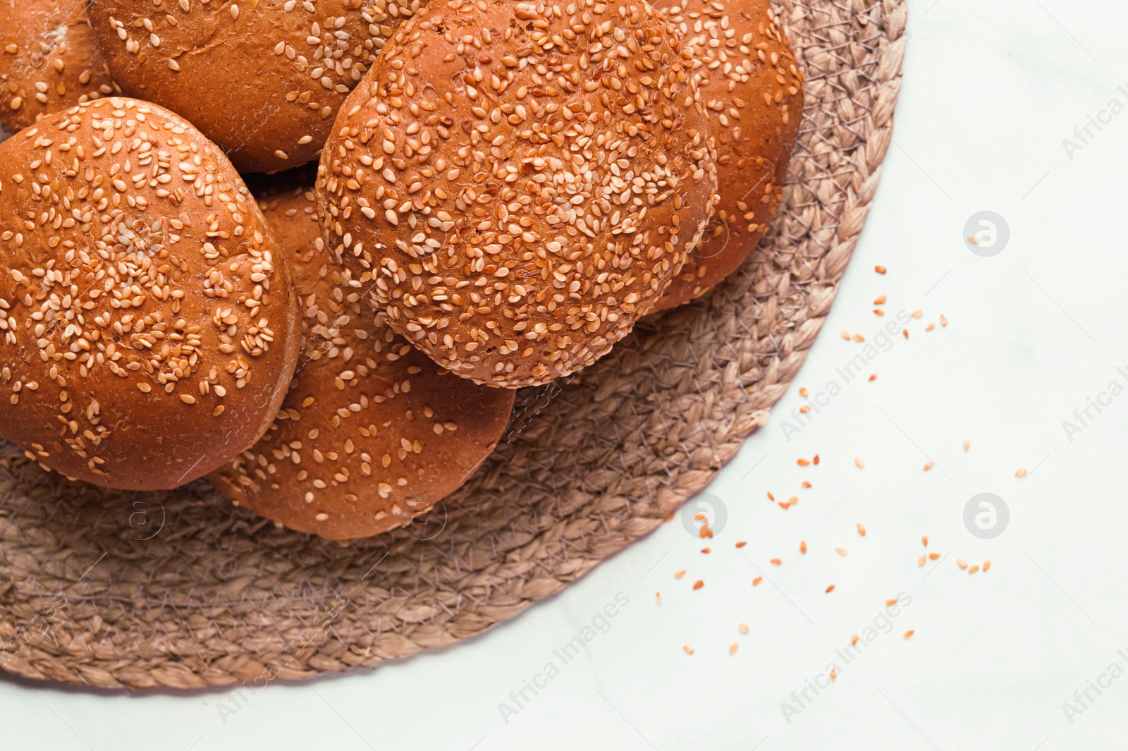 Photo of Fresh buns with sesame seeds on white marble table, flat lay. Space for text