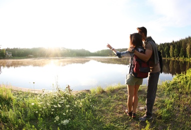 Photo of Young couple on shore of beautiful lake, wide-angle lens effect. Camping season