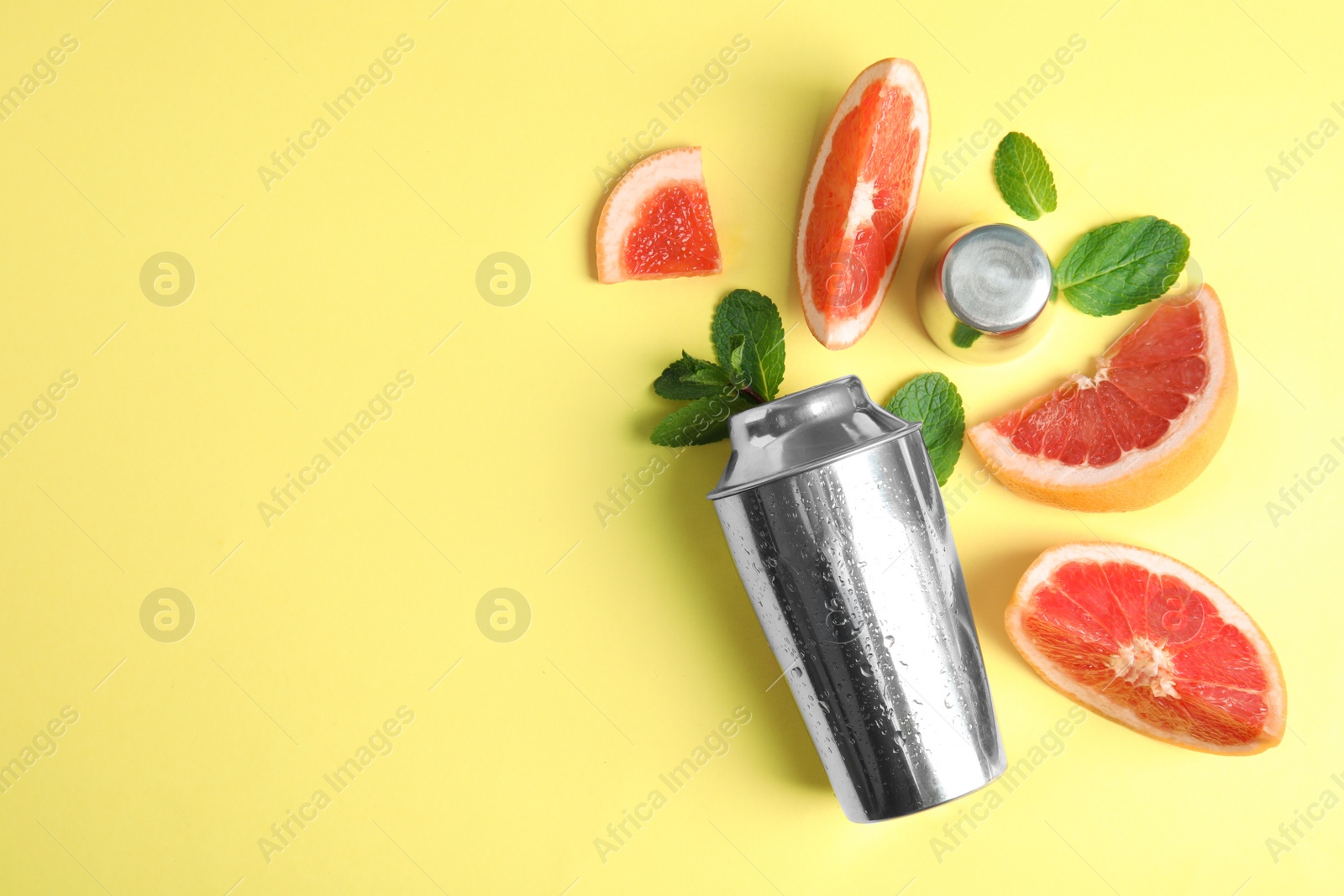 Photo of Flat lay composition with shaker and grapefruit slices on color background. Space for text