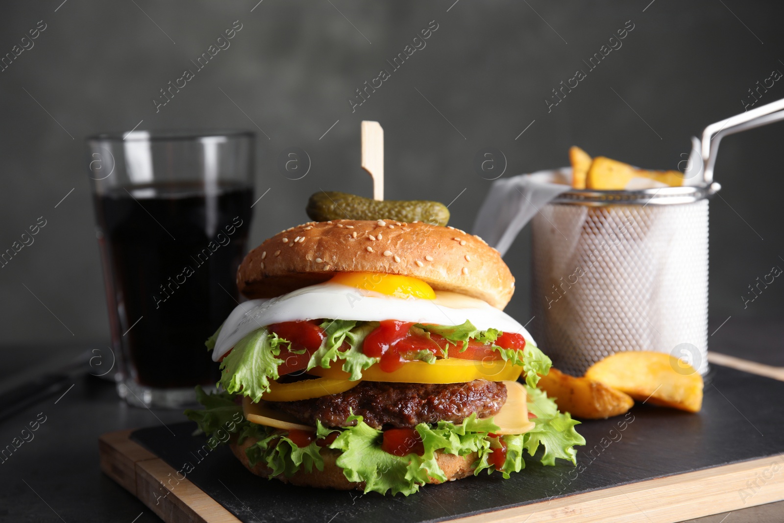 Photo of Tasty burger with fried egg on board against dark background