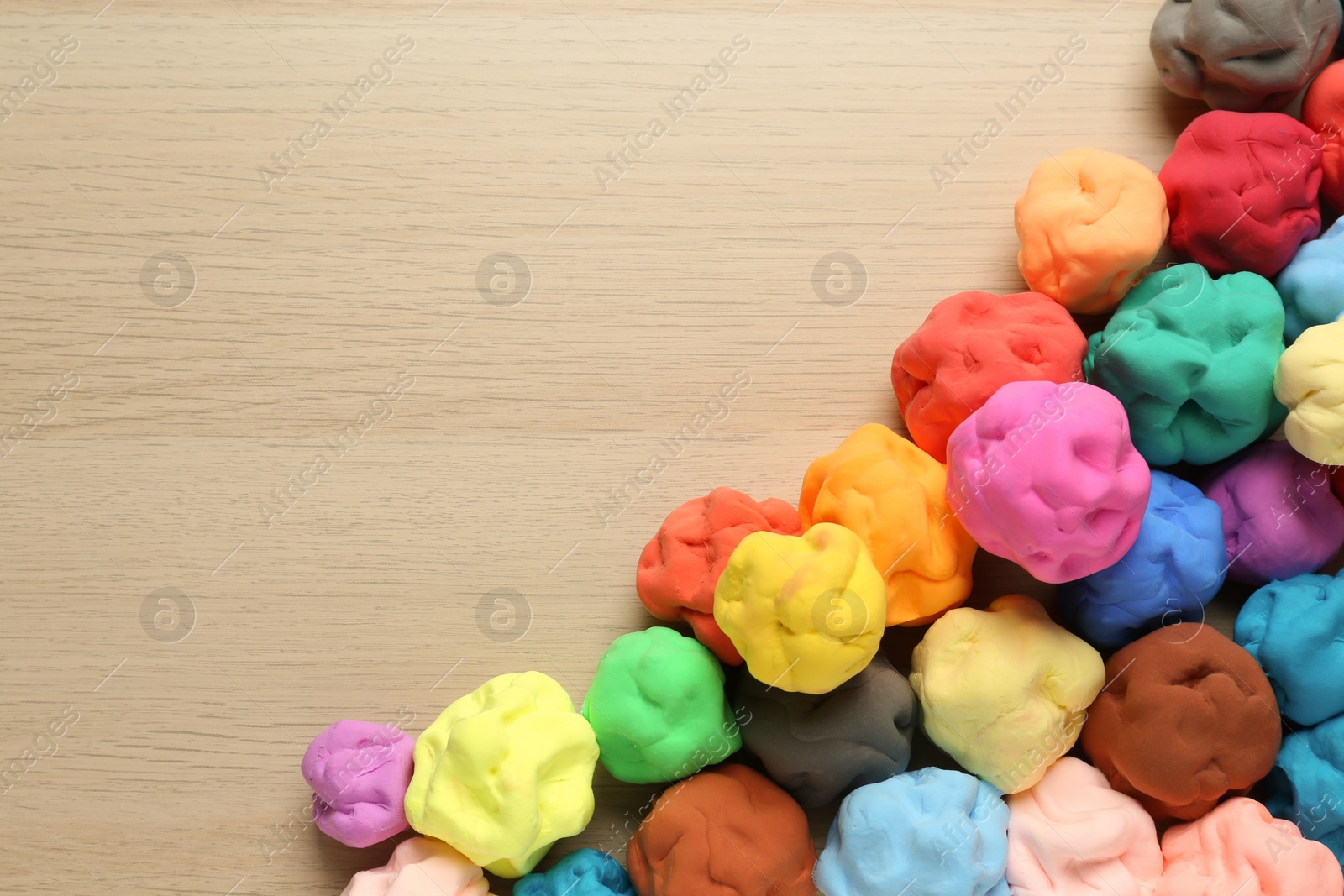Photo of Different color play dough on wooden table, flat lay. Space for text