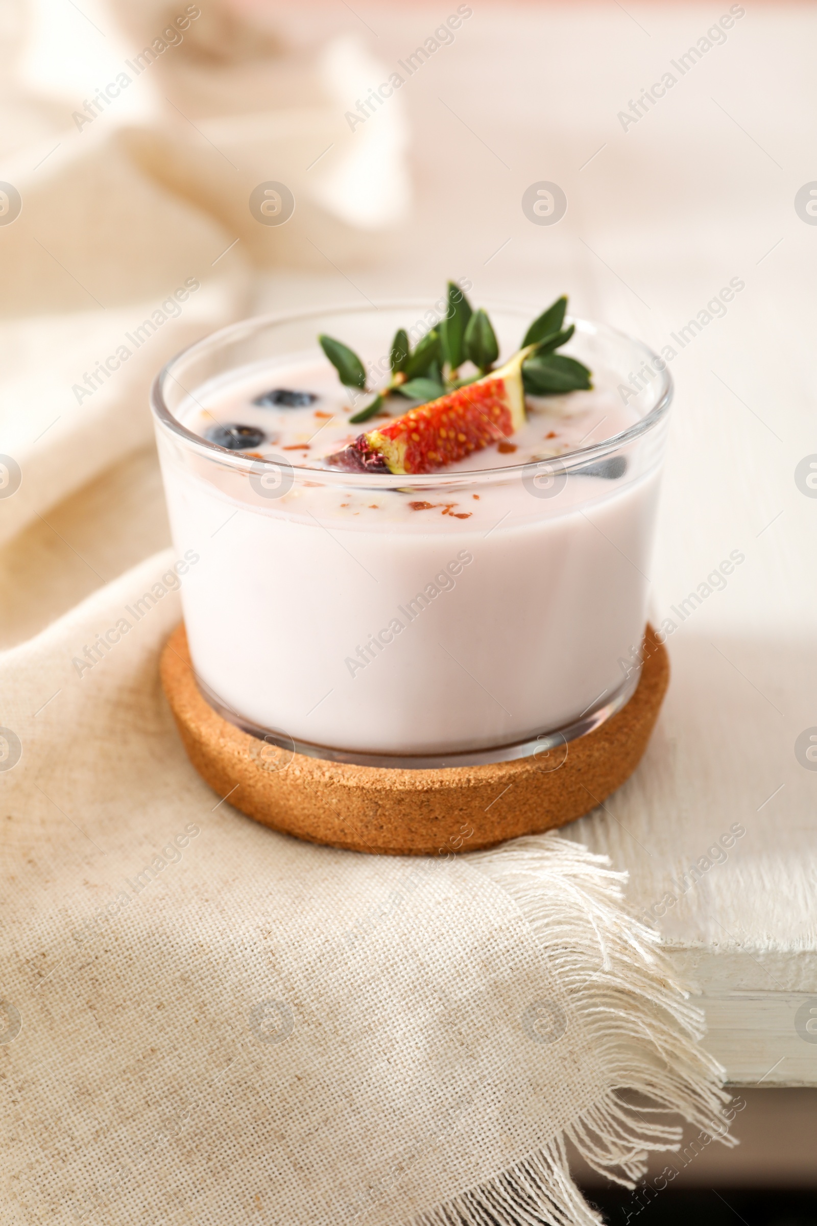 Photo of Delicious fig smoothie in glass on white wooden table