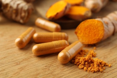 Photo of Aromatic turmeric powder and pills on wooden table, closeup