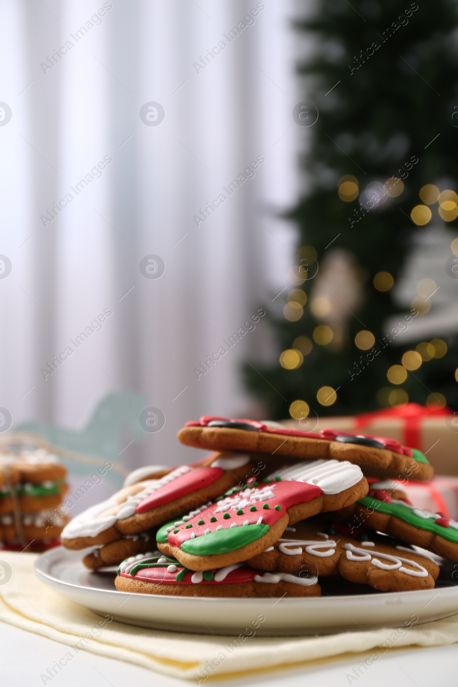 Photo of Decorated cookies on white table against blurred Christmas lights