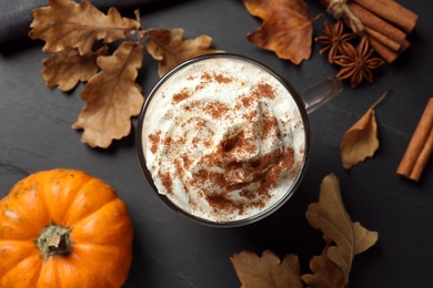 Photo of Delicious pumpkin latte on black table, top view