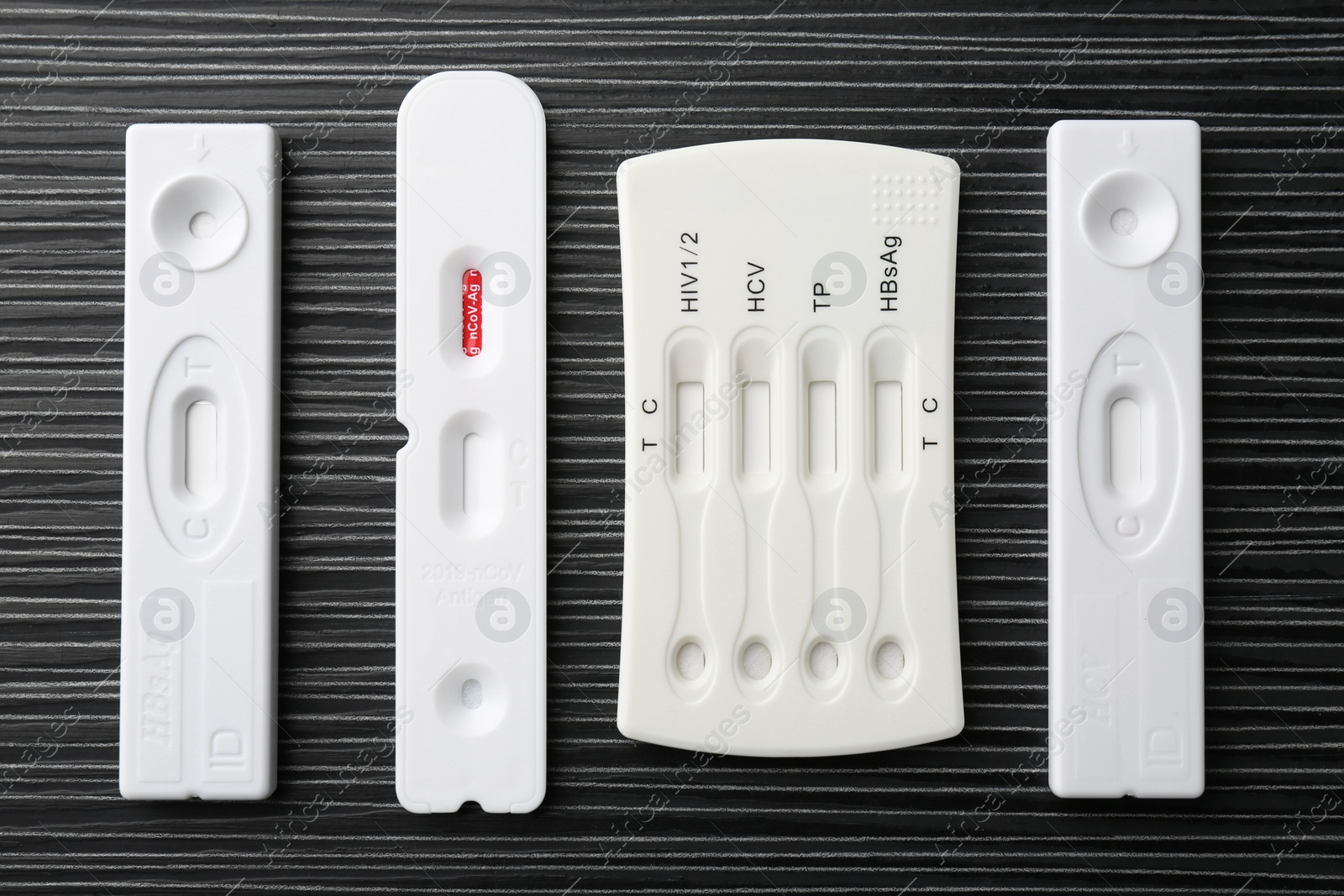 Photo of Different disposable express tests on black wooden table, flat lay