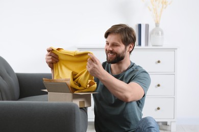 Photo of Happy man with parcel at home. Internet shopping