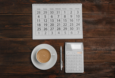 Photo of Flat lay composition with calendar and cup of coffee on wooden table