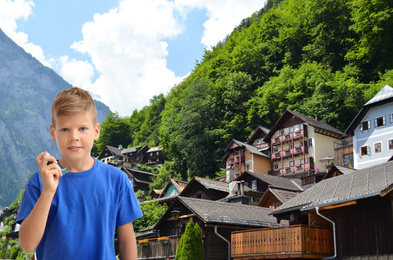 Image of Little boy with asthma inhaler and mountain village on background. First emergency medical aid