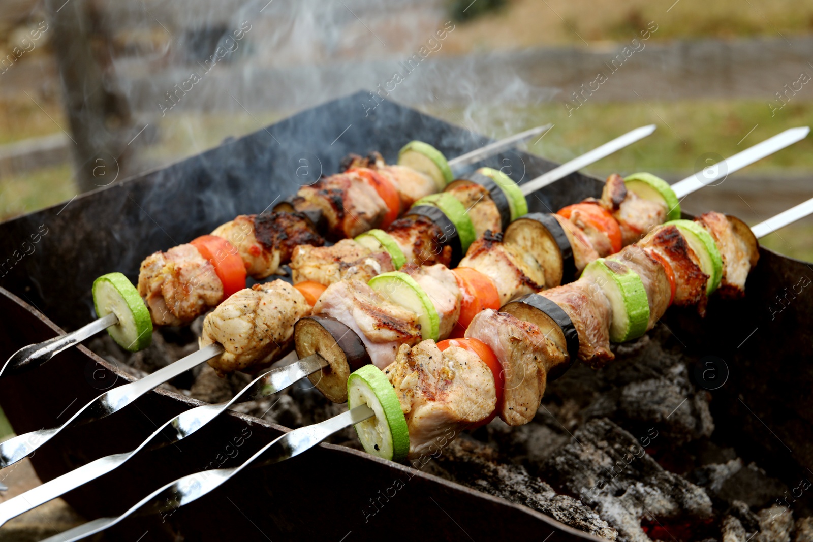 Photo of Cooking meat and vegetables on brazier outdoors