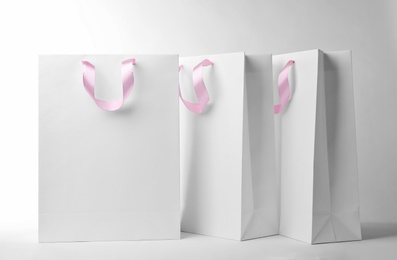 Photo of Paper shopping bags with ribbon handles on white background. Mockup for design