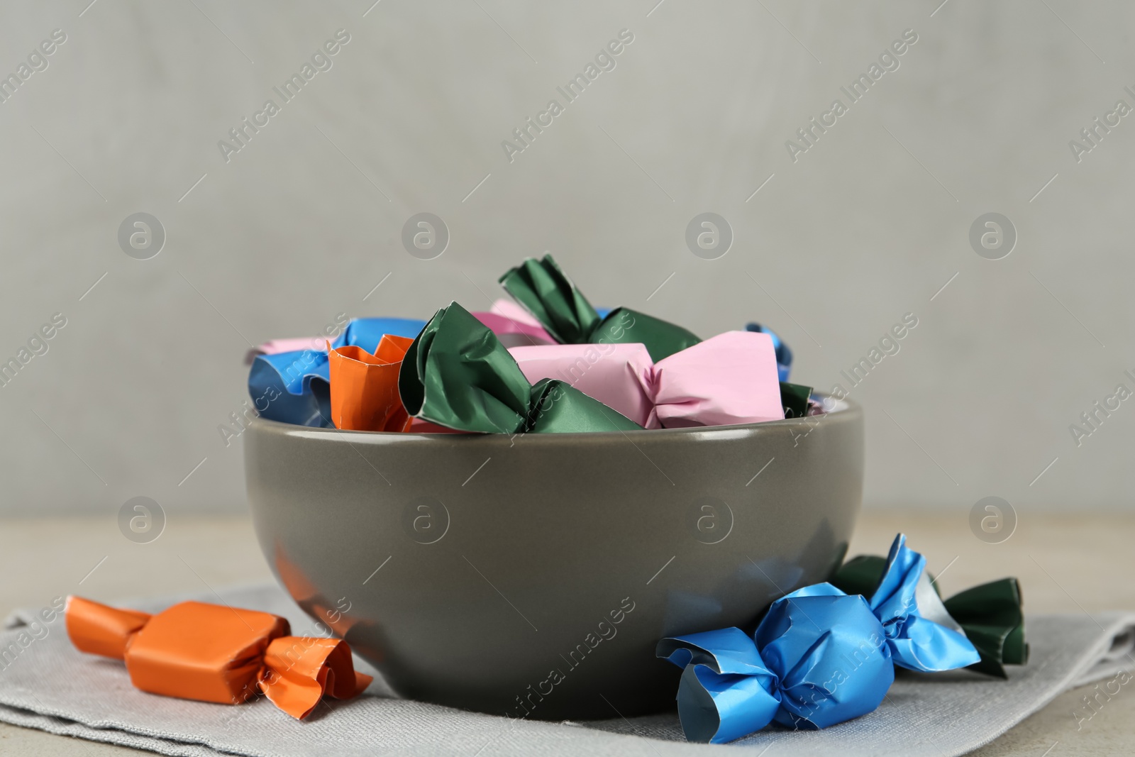 Photo of Candies in colorful wrappers on light beige table, closeup