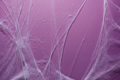 Photo of Creepy white cobweb hanging on violet background