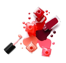 Photo of Spilled different nail polishes with bottles on white background, top view