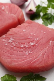 Photo of Raw tuna fillets and spices on white table, closeup