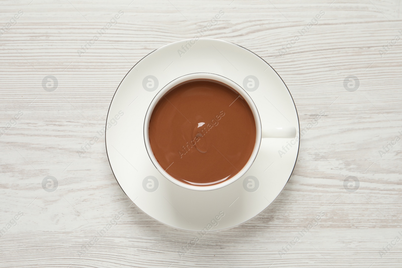 Photo of Yummy hot chocolate in cup on white wooden table, top view