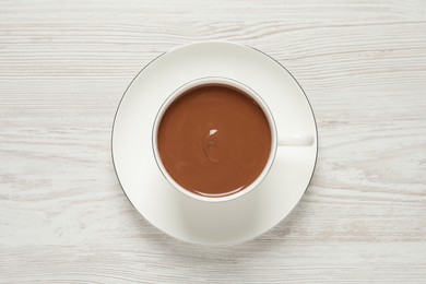 Photo of Yummy hot chocolate in cup on white wooden table, top view