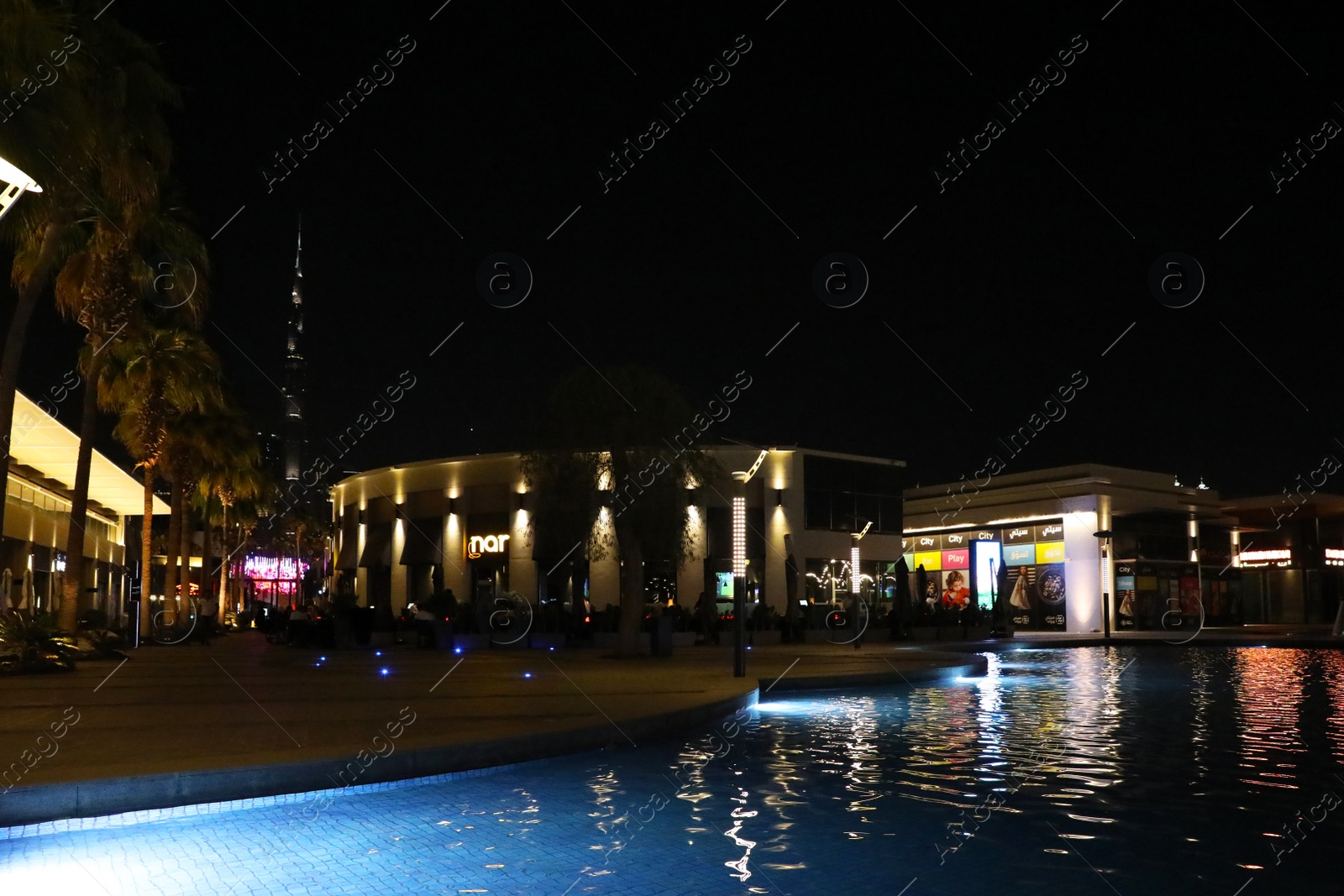 Photo of DUBAI, UNITED ARAB EMIRATES - NOVEMBER 04, 2018: Night cityscape with illuminated buildings, palms and pool