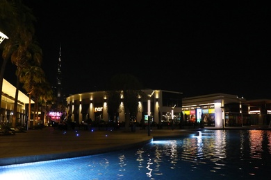 DUBAI, UNITED ARAB EMIRATES - NOVEMBER 04, 2018: Night cityscape with illuminated buildings, palms and pool