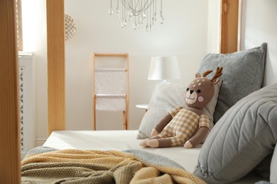 Photo of Comfortable wooden house bed with cushions and toy in child room. Interior design