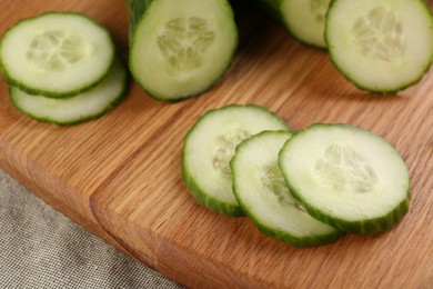 Photo of Cut ripe cucumber on wooden board, closeup