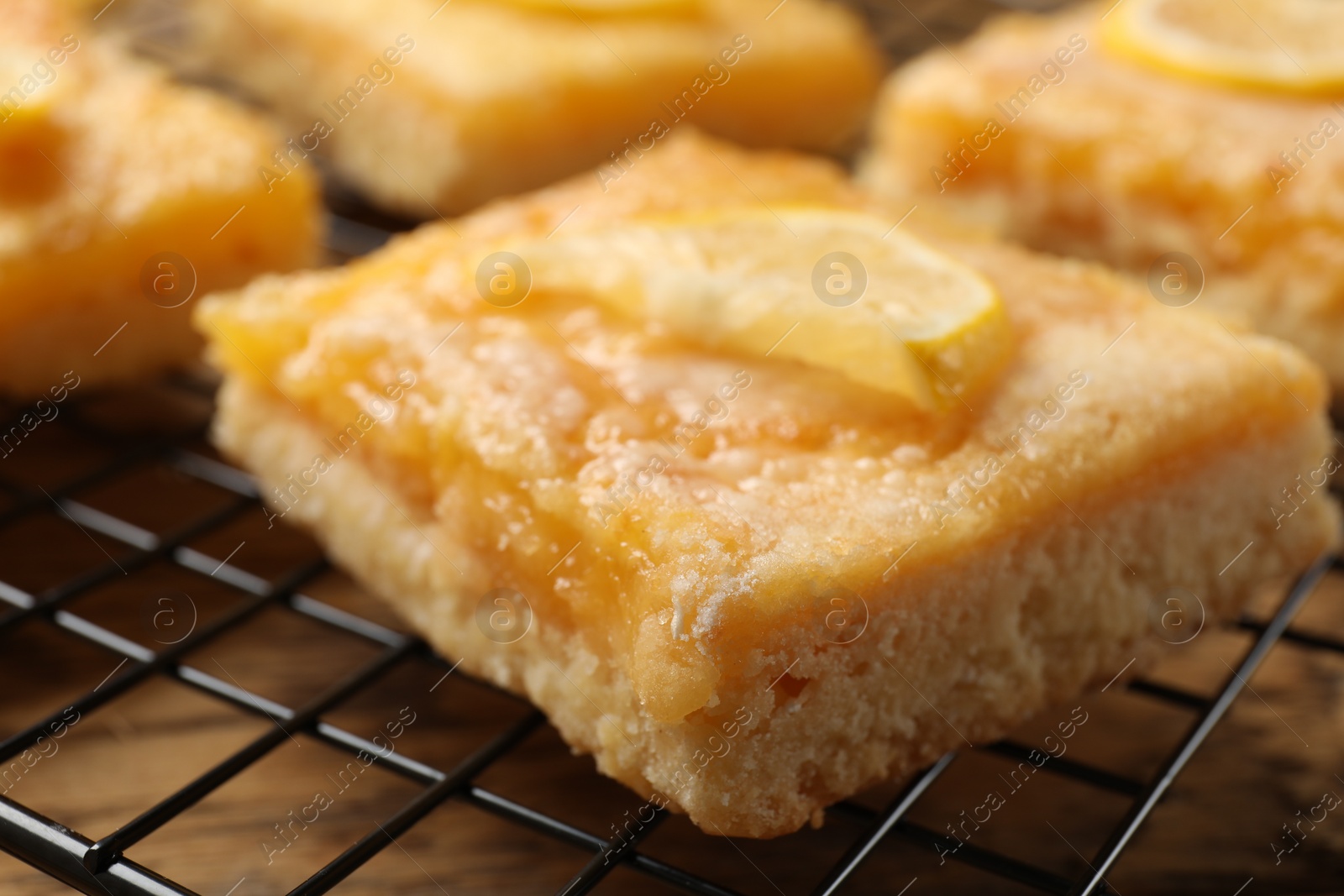 Photo of Tasty lemon bars on cooling rack, closeup