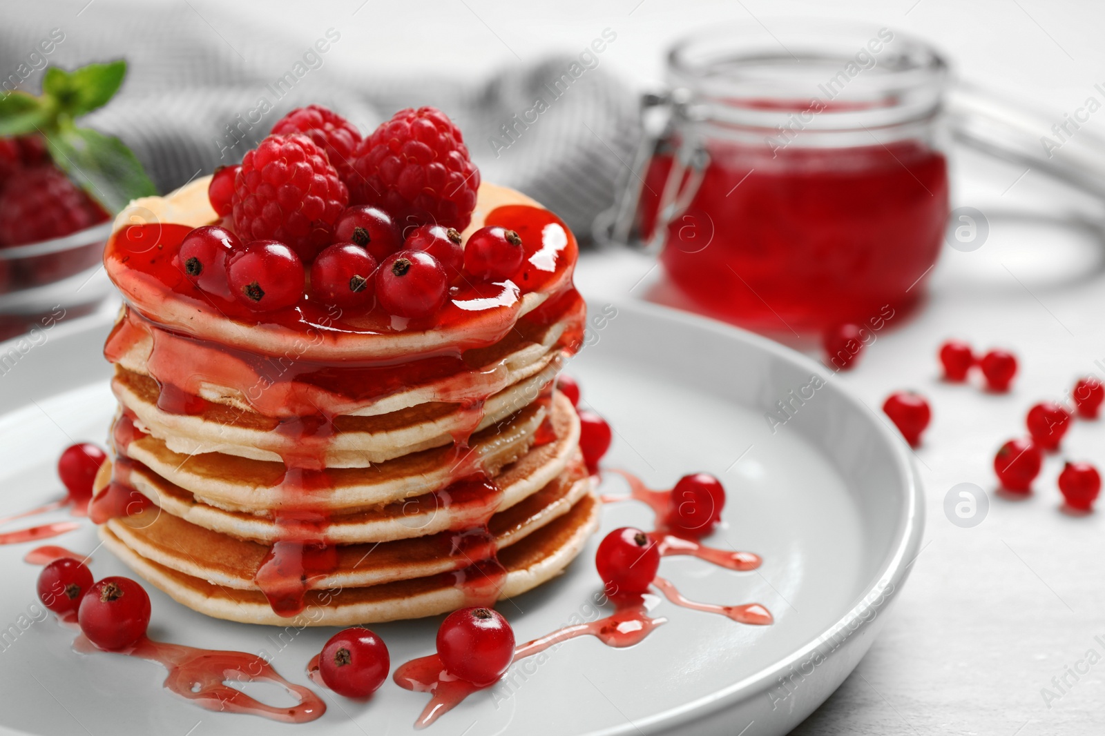 Photo of Delicious pancakes with fresh berries and syrup on white table