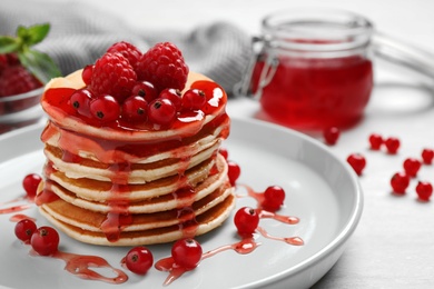 Delicious pancakes with fresh berries and syrup on white table