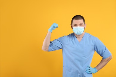 Photo of Doctor with protective mask showing muscles on yellow background, space for text. Strong immunity concept