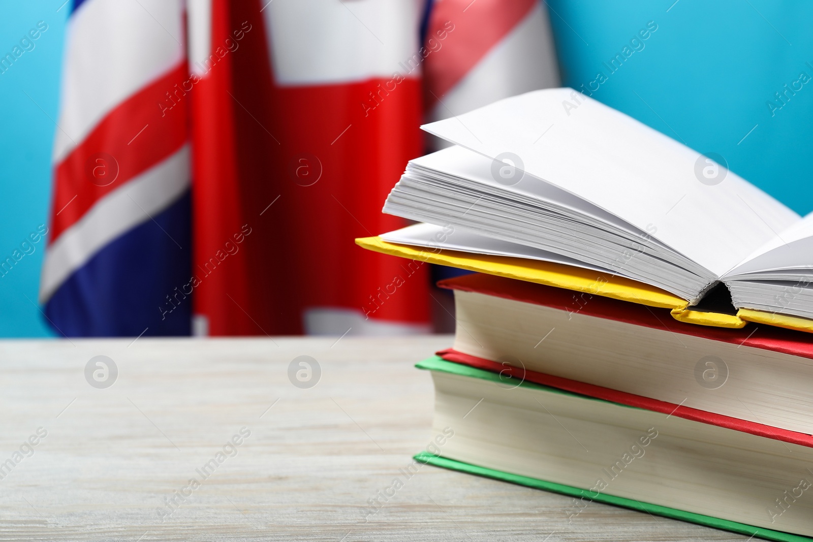 Photo of Learning foreign language. Different books on wooden table near flag of United Kingdom, space for text