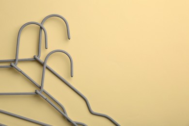 Photo of Hangers on pale yellow background, top view. Space for text