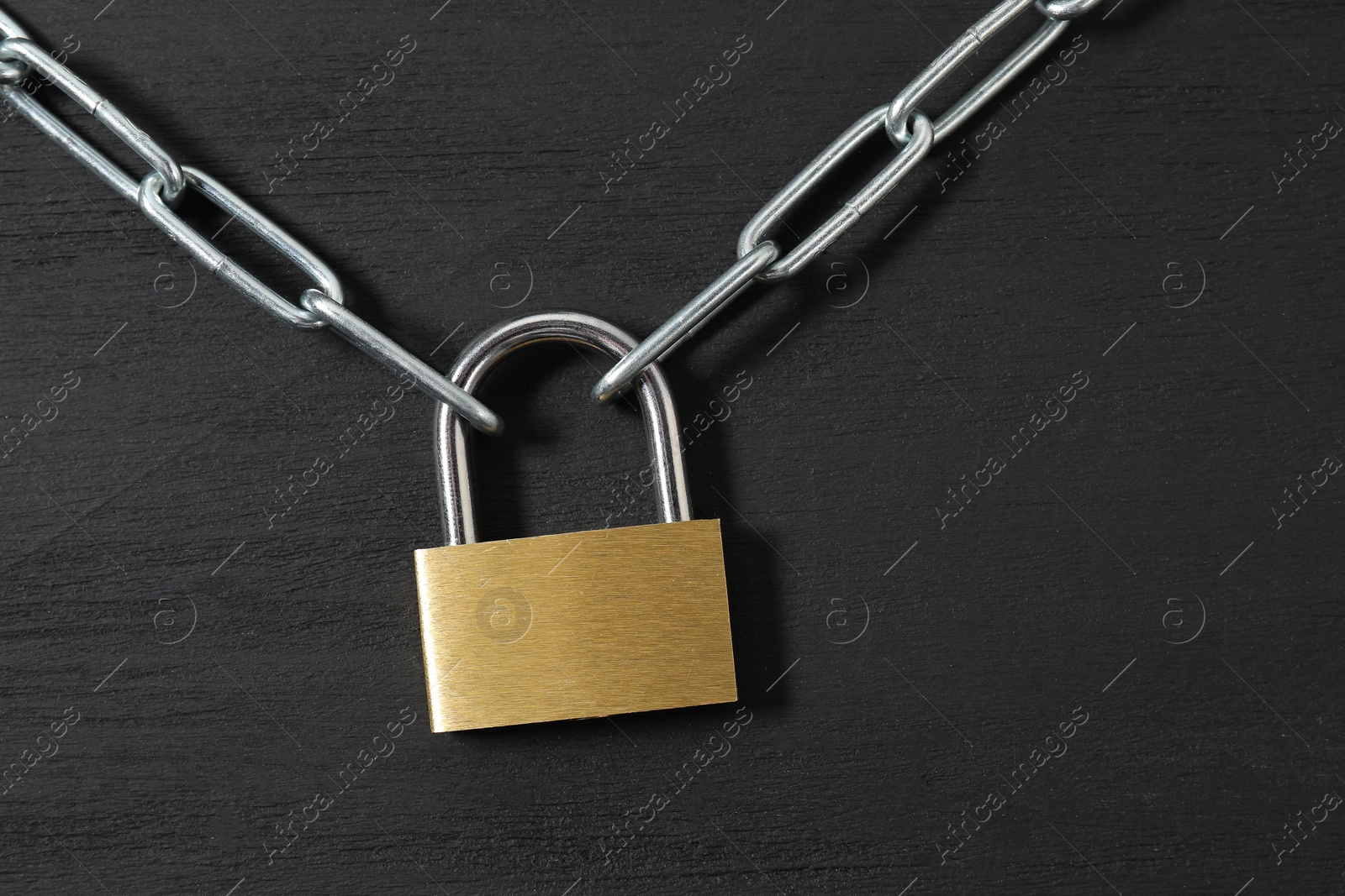 Photo of Steel padlock with chain on black wooden table, top view