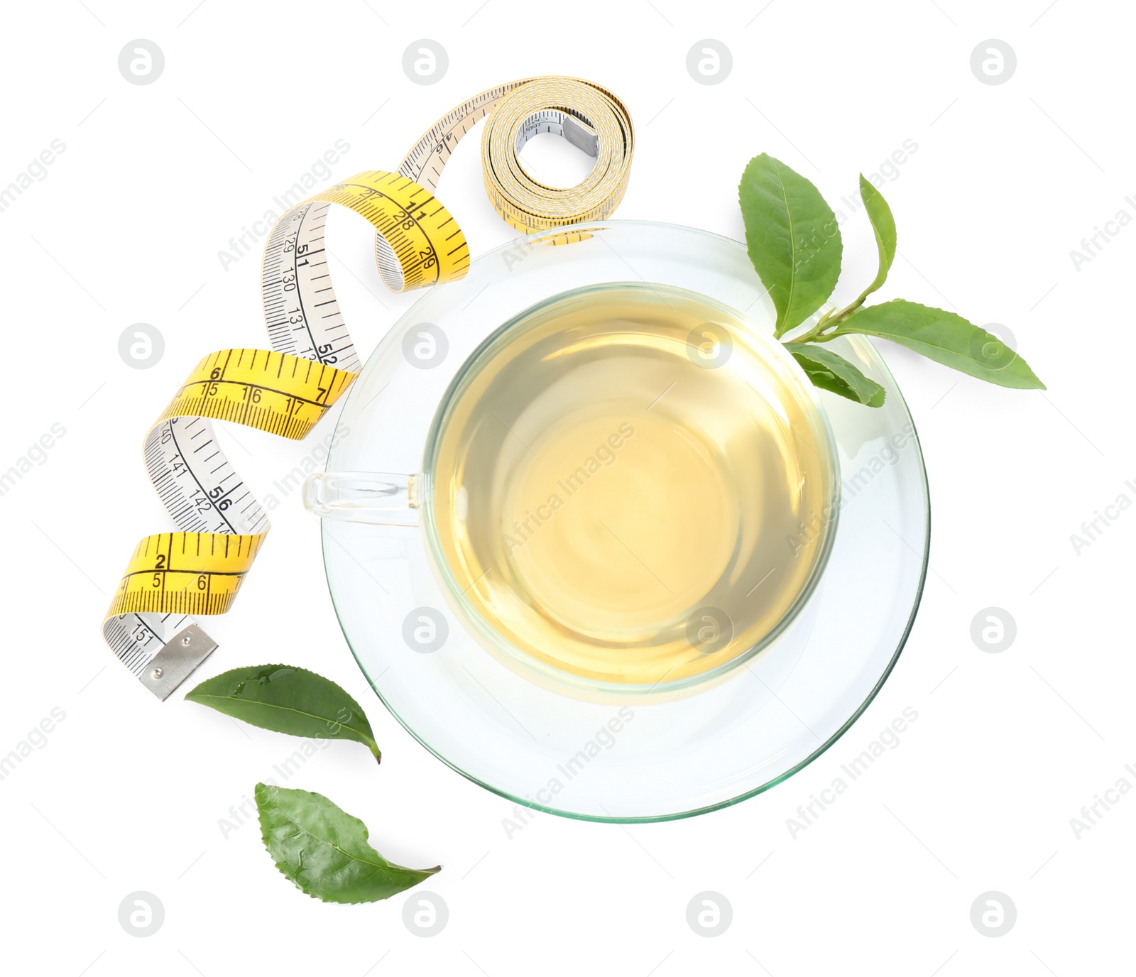 Photo of Glass cup of diet herbal tea, green leaves and measuring tape on white background, top view