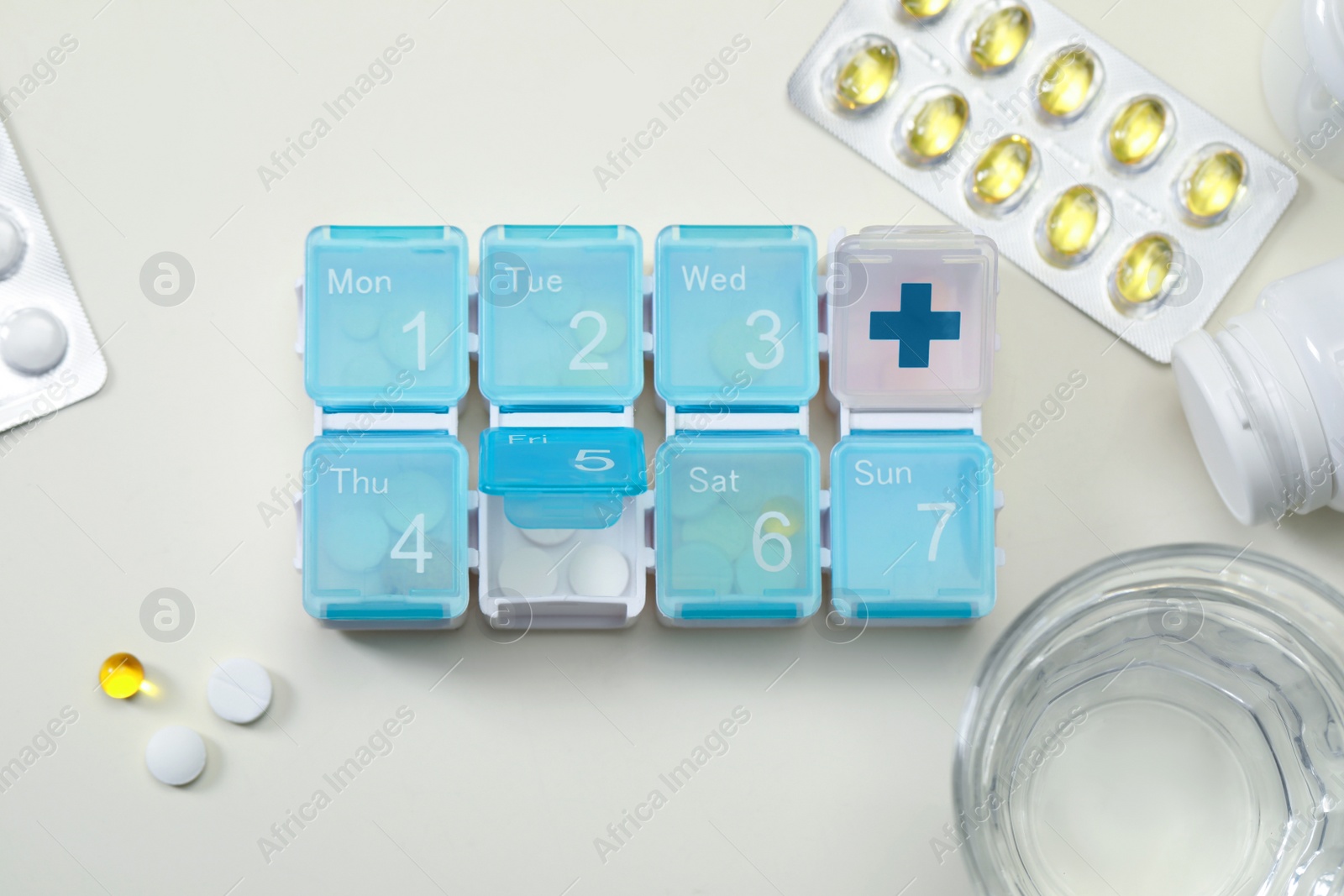 Photo of Plastic pill box and different medicaments on white table, flat lay