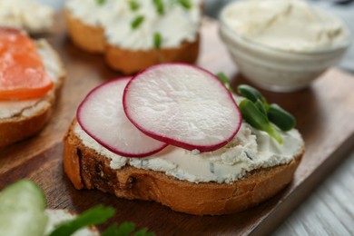 Photo of Toasted bread with cream cheese, radish and microgreen on wooden board, closeup