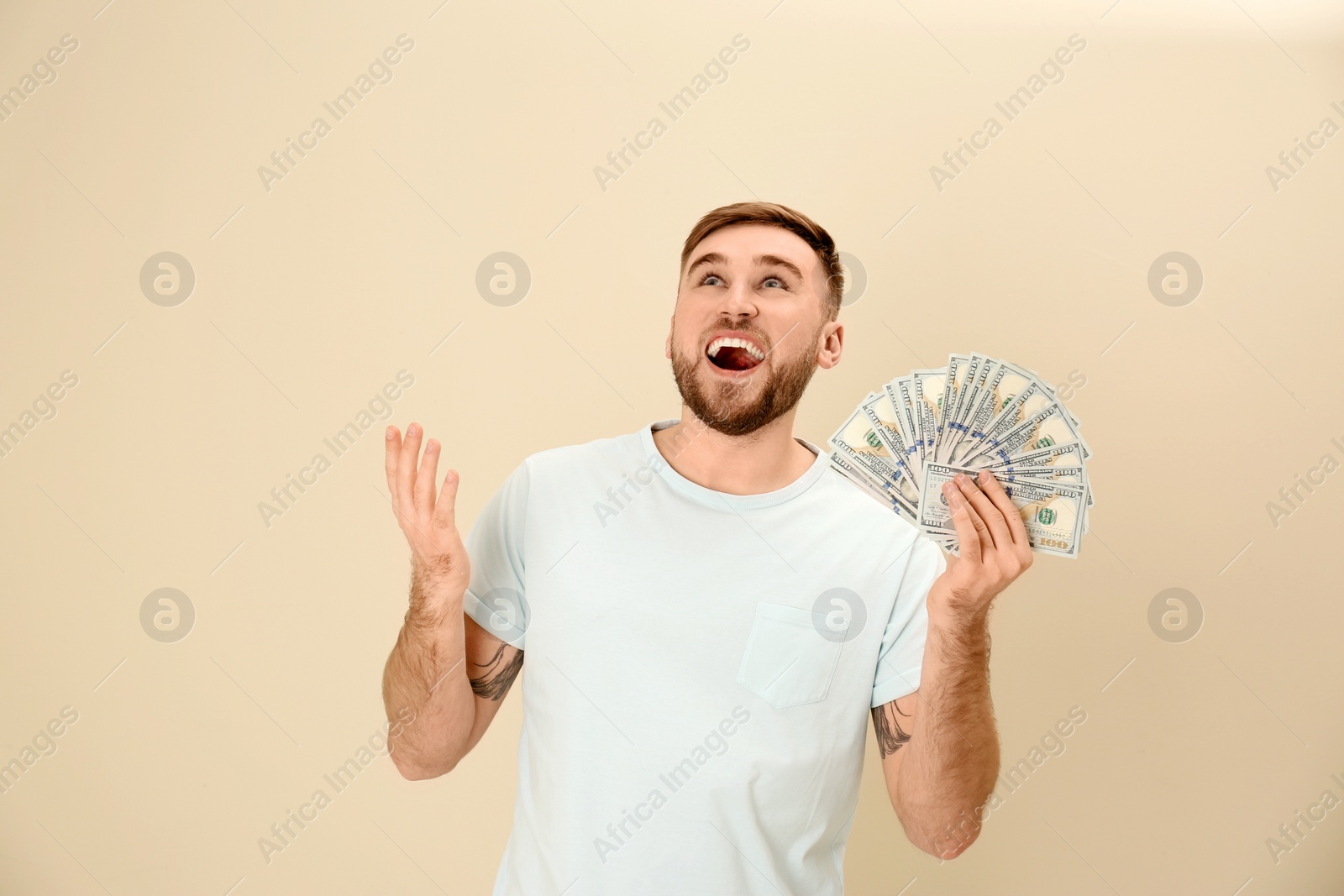 Photo of Portrait of emotional young man with money on color background