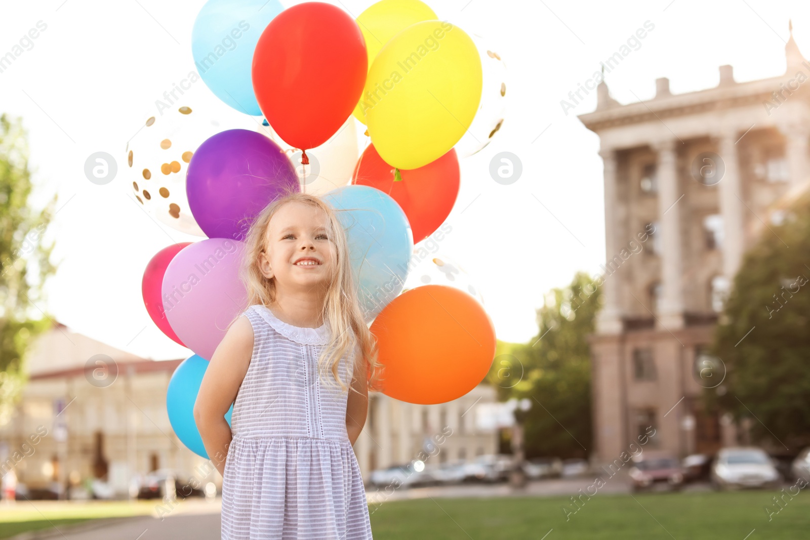 Photo of Cute little girl with colorful balloons outdoors on sunny day